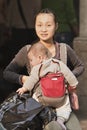 Young Chinese mother with baby in carry bag, Guanghzhou, China